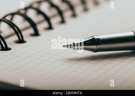 Opened notepad in a cage with an automatic plastic ballpoint pen close-up. Stock Photo