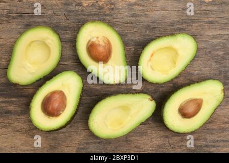 Slices Of Avocado Cut In Half On Wooden Table Stock Photo