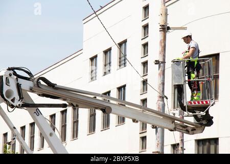 Belgrade, Serbia - April 24, 2020: Construction worker in crane basket, cherry picker, installing metal holder on street light pole Stock Photo