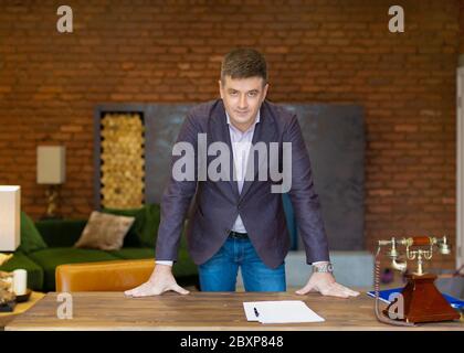 Portrait of a middle-aged businessman leaning on his desk. Business concept. Stock Photo