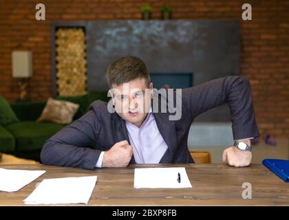 Portrait of an angry middle-aged businessman leaning on his desk. Business concept. Stock Photo