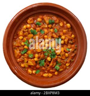 Chana Masala with sweet potatoes. Spicy, vegetarian chickpea curry in an earthenware dish. Isolated on white background. Stock Photo
