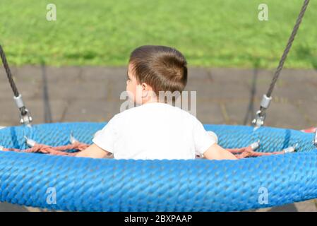 Boy swinging on the playground at the day time Stock Photo