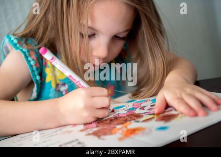 A 5-year-old girl uses felt tip crayons