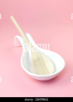 A wooden spoon in a resting laddle isolated against a pink background Stock Photo