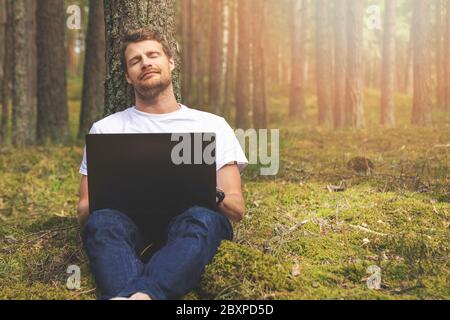 remote work in nature - man with laptop relaxing in the woods Stock Photo