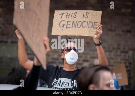 Woman protester, wearing a face mask and hooded top, holds up a 'Justice 4 Belly' sign at the Black Lives Matter UK protest, Parliament Square UK Stock Photo