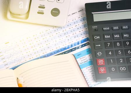 A calculator, a landline phone with buttons, a diary and financial documents on the desktop. Business concept and accounting Stock Photo