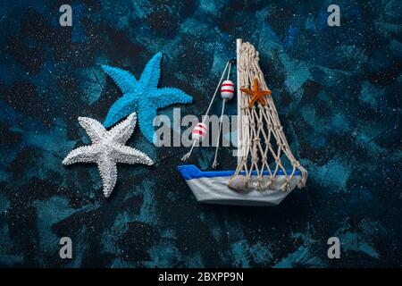 Sea composition with a boat and seashells on a dark blue background. Selective focus Stock Photo
