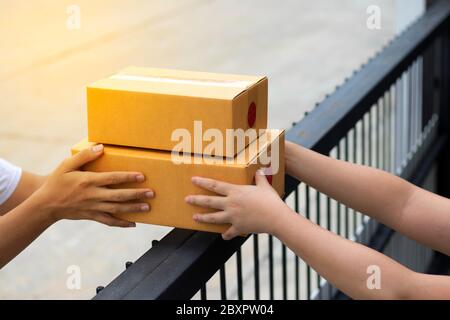 Courier service is delivering the brown box to the recipient. The shipping company delivers the goods to the recipient at the front door.