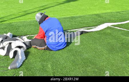 The mechanic is repairing the ground of the football field. Stock Photo