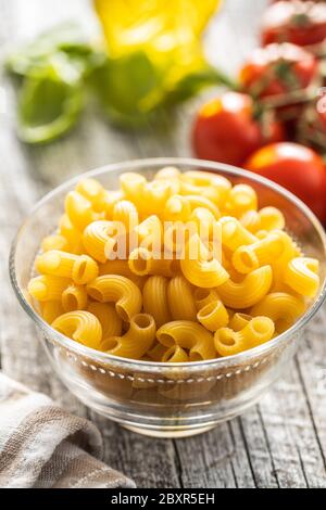 Raw italian pasta in glass bowl on wooden table. Stock Photo