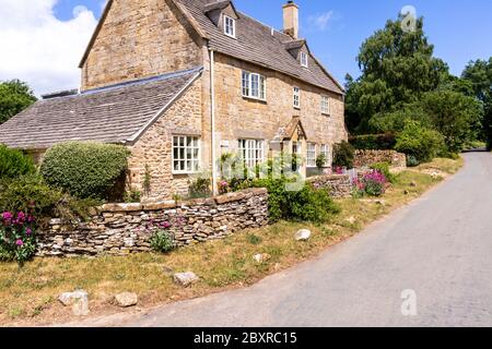 A stone cottage beside the lane in the Cotswold village of Cutsdean, Gloucestershire UK Stock Photo