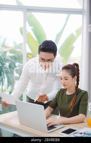 Wide shot of nice man and woman surfing in laptop while sitting at table Stock Photo