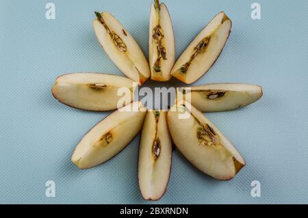 Ordered slices of red organic apple on light blue textured background Stock Photo