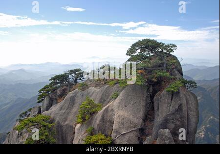 Huangshan Mountain in Anhui Province, China. View of a rocky outcrop surmounted by pine trees on the path to Lotus Peak, the highest point. Stock Photo