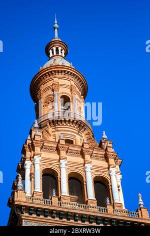 Ancient architecture tower view in Plaza de España against blue sunny clear sky. Main landmark popular place for tourists, Spain Stock Photo