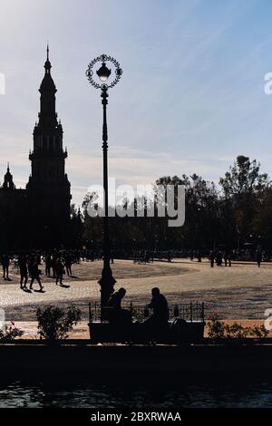 Architecture silhouette against clear sky of ancient tower in Plaza de Espana, lot of people visited famous place, main landmark of Seville city Stock Photo