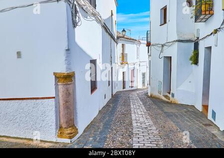 The ancient stone column is imbedded in corner of old white house in residential neighborhood of Arcos, Spain Stock Photo