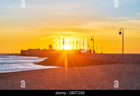 La Caleta beach is perfect place to watch bright sunset on the coast of Atlantic Ocean behind the rampart of San Sebastian Castle, Cadiz, Spain Stock Photo