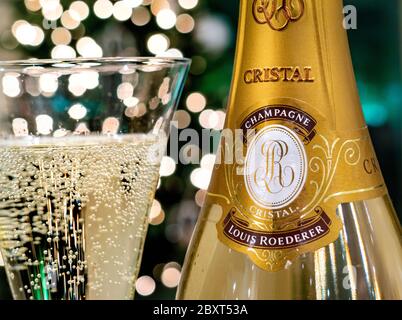 CRISTAL CHAMPAGNE Bottle and freshly poured glass of Louis Roederer Cristal luxury champagne with sparkling party celebration  lights in background Stock Photo