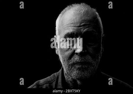 Black and white portrait of an old man, marked by life, looking thoughtfully into the camera. Stock Photo