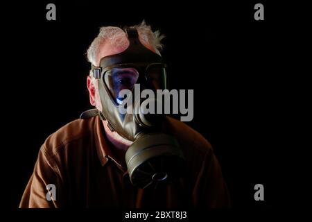 Threatening scenario an older man with gas mask protects himself from the corona virus. People's fear of the virus is growing. Stock Photo