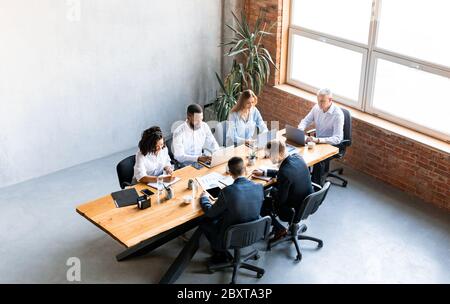 Diverse Colleagues Working Sitting Together In Modern Office, High-Angle Shot Stock Photo