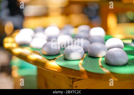 mini purple sweet steaming bun on decorative palm leaf on wood plate in outdoor field. Stock Photo