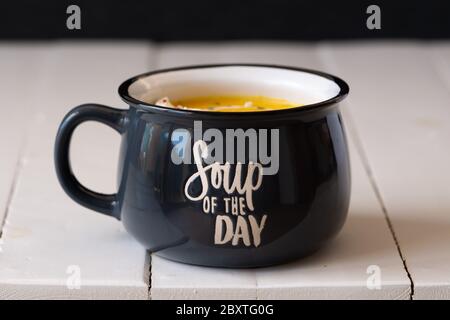 Pumpkin soup in a blue bowl isolated. Inscription: soup of the day on a bowl. Vegetarian lunch or dinner. Healthy food concept.  Stock Photo