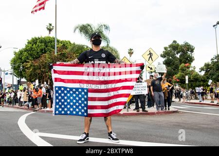 Man carrying an upside down American flag at a peaceful protest honoring George Floyd in Los Angeles, CA Stock Photo