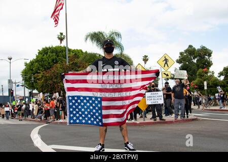 Man carrying an upside down American flag at a peaceful protest honoring George Floyd in Los Angeles, CA Stock Photo