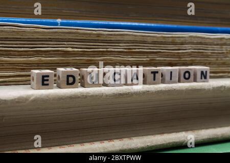Close up of isolated word education spelled by letter wood tiles on pile with yellowed old books (focus on word) Stock Photo