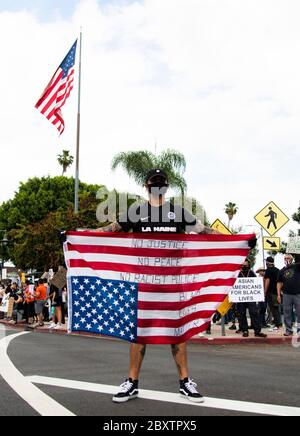 Man carrying an upside down American flag at a peaceful protest honoring George Floyd in Los Angeles, CA Stock Photo