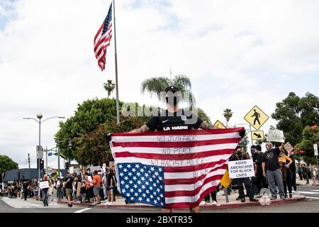 Man carrying an upside down American flag at a peaceful protest honoring George Floyd in Los Angeles, CA Stock Photo
