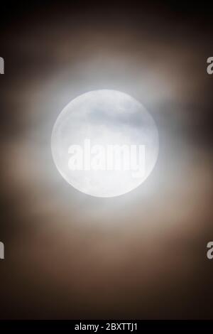 Full Strawberry Moon  through clouds over Rocky Mountains, Salida, Colorado, USA Stock Photo