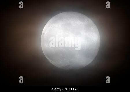 Full Strawberry Moon  through clouds over Rocky Mountains, Salida, Colorado, USA Stock Photo