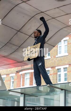 A black man stands with his fist raised on top of a bus stop at Vauxhall bus station, during Black Lives Matters protest in London, 6 June 2020 Stock Photo