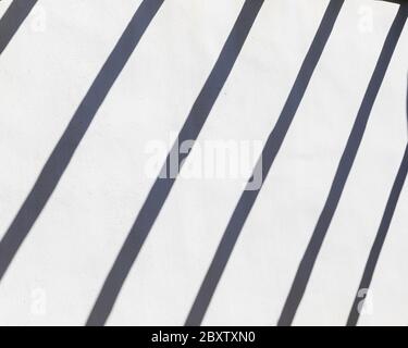 Shadow Lines. Abstract background od whitewashed  wall with  grey line creating shadows from a pergola. Stock image. Stock Photo