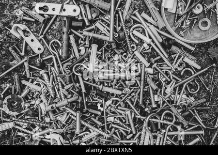 Black and white photo of assorted metalware bolts and nuts flat lay. Work tools closeup. Abstract industrial background for Fathers Day Stock Photo