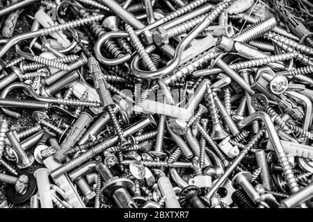 Pile of many assorted metalware bolts and nuts. Black and white photo of work tools closeup. Abstract industrial background for Fathers Day Stock Photo