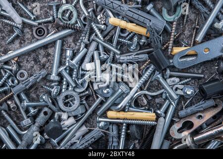 Blue filter flat lay of steel bolts and nuts, hooks and dowels on grunge stone background with copy space. Soft focus to grunge metal fastener fitting Stock Photo