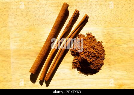 HOLIDAY SPICE: Cinnamon sticks and the ground up version of it rest side by side on a wooden cutting board. Stock Photo