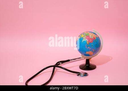 Earth globe with stethoscope on pastel background. Stock Photo