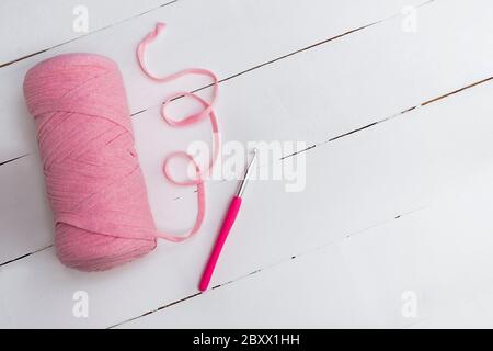 Crocheting and home hobby concept. Top view of crochet work with crochet  hook and pink yarn on white wooden table Stock Photo - Alamy