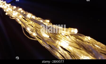 Close up lights of garland on the wall. Glowing electric garland on a black background. Stock Photo