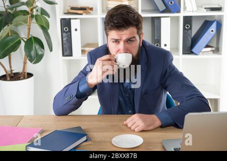 My energy. Office life routines. Respectable ceo. First coffee. Man handsome boss sit in office drinking coffee. Comfy workspace. Good morning. Bearded hipster formal suit relaxing with coffee. Stock Photo