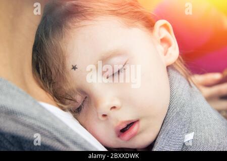 Little girl sleeping on her mother chest in baby wrap carrier Stock Photo