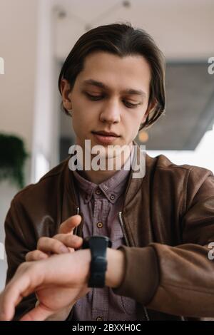 Young positive man using smart watch application, touching digital screen, receiving email. Wireless technology, innovation concept Stock Photo