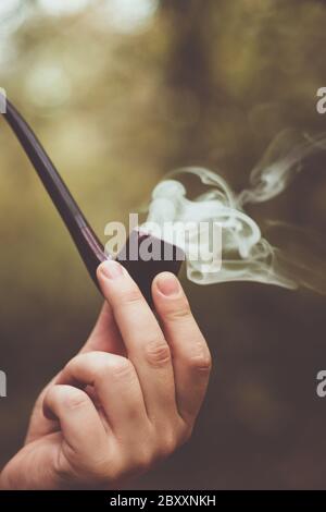 Close up smoking tobacco pipe on blurred background outdoor Stock Photo